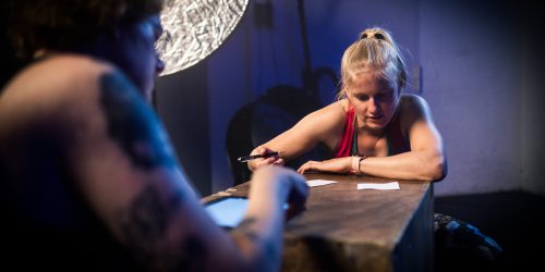 Frau sitzt lesend hinter einer Kiste, auf der ein Papier liegt