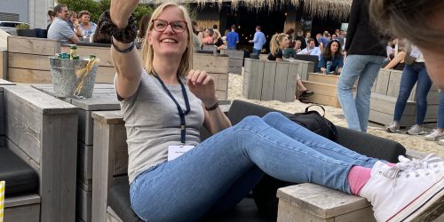 Foto von Frau in Strandbar, während sie in das Handy schaut um ein Selfie zu machen